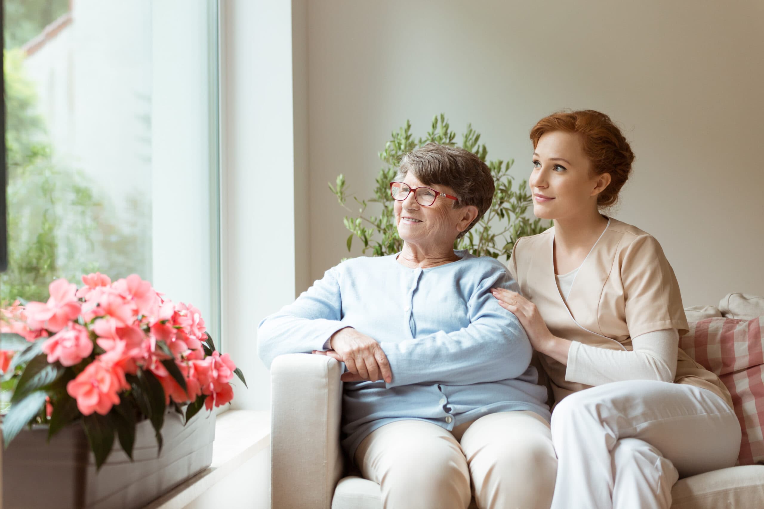 Caregiver and elderly resident sitting together by a sunlit window